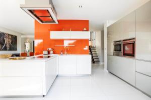 een keuken met witte kasten en een oranje muur bij Villa Azif - Superbe Maison avec Piscine - St Pierre Azif in Saint-Pierre-Azif