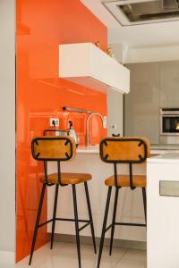 een oranje keuken met 2 barkrukken bij Villa Azif - Superbe Maison avec Piscine - St Pierre Azif in Saint-Pierre-Azif
