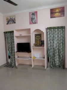 P. G. REDDY HOME STAY في تيروباتي: غرفة معيشة وستارين وتلفزيون