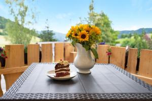 einen Tisch mit einem Stück Kuchen und eine Vase mit Blumen in der Unterkunft Haus Bergruh Fuchsbau in Todtnauberg