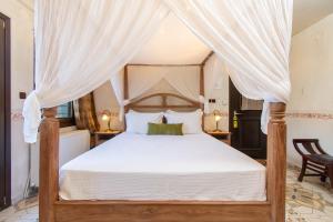 a bedroom with a canopy bed with white sheets at Oreiades Guesthouse in Parthenonas