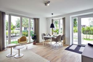 un salon avec une table, des chaises et des fenêtres dans l'établissement Lüttjeod Apartmentvilla Lüttjeod Apartmentvilla 03, à Langeoog