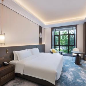 um quarto com uma grande cama branca e uma janela em voco Xiong'An em Baoding
