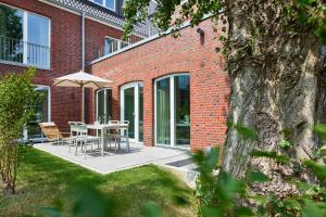 un patio avec une table et un parasol dans l'établissement Lüttjeod Apartmentvilla Lüttjeod Apartmentvilla 03, à Langeoog