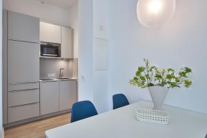 ein weißes Esszimmer mit einem weißen Tisch und blauen Stühlen in der Unterkunft Lüttjeod Apartmentvilla Lüttjeod Apartmentvilla 06 in Langeoog