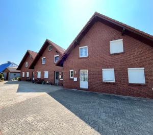 a brick building with white windows and a driveway at Naturstrand Apartment - 86m² - 4 Betten - Parkplatz in Hagermarsch