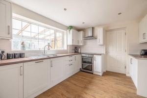 a kitchen with white cabinets and a large window at 3-Bed Family Home with Parking & Large Garden in Windsor