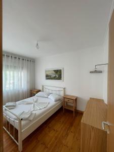 Dormitorio blanco con cama y mesa en Vourtaréa Guesthouse, en Himare