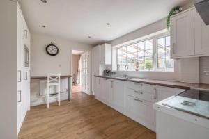 a kitchen with white cabinets and a clock on the wall at 3-Bed Family Home with Parking & Large Garden in Windsor