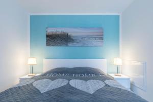 a bedroom with a bed with two lamps and a blue wall at FeWo Blåkulle im Haus Seeblick - Wohnung 11 in Hohenkirchen