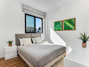 a white bedroom with a bed and a window at Sanders Olive in Paphos City