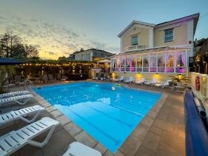 a swimming pool with chairs and a house at Riviera Lodge Hotel in Torquay