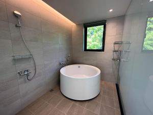 y baño con bañera grande y ducha. en Villa LOHERB, en Dongshan