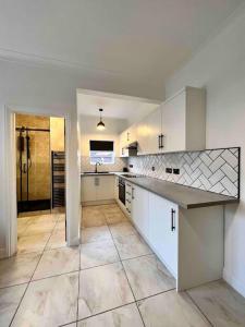 a large kitchen with white cabinets and a tile floor at The Saddle Inn, Snetterton Circuit in Norwich