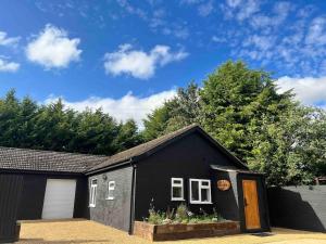 una casa negra con una puerta y un garaje en The Saddle Inn, Snetterton Circuit, en Norwich