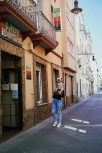 a woman standing on a street in front of a building at LOFT HOSTAL Group in Lloret de Mar