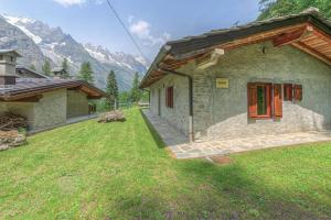 a small stone house with red doors in a yard at Baita Girasole Val Veny in Courmayeur