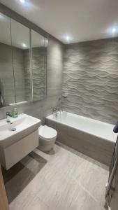a bathroom with a tub and a toilet and a sink at Luxury 2 Bed 2 Bath Penthouse Apartment in Hendon