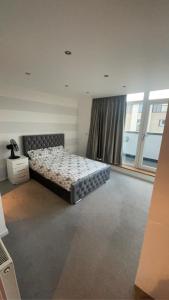 a bedroom with a bed and a large window at Luxury 2 Bed 2 Bath Penthouse Apartment in Hendon