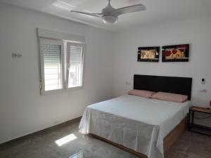 um quarto branco com uma cama e 2 janelas em Villa a 10 km de Alicante y playas em Elche