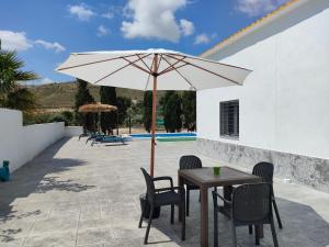 Villa a 10 km de Alicante y playas في إلتشي: طاولة وكراسي مع مظلة على الفناء