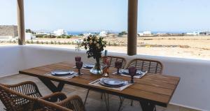 a wooden table with chairs around it with a view of the beach at Gaia Mykonos Villas & Suites in Tagou
