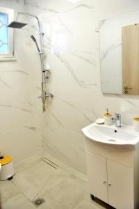 a white bathroom with a sink and a shower at J&M FALIRAKI in Faliraki