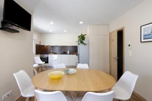 uma cozinha e sala de jantar com uma mesa de madeira e cadeiras brancas em Pontes Guest House em Arcozelo