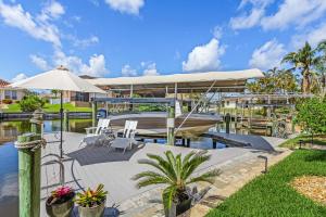 een huis met een boot op het water met een patio bij LUXURY VILLA AWENASA * experience the vacation of your dreams in Cape Coral