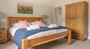 a bedroom with a wooden bed with pink and white pillows at Keepers Cottage in Rusland +18 photos