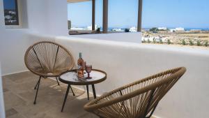 2 Stühle und ein Tisch mit einem Drink drauf in der Unterkunft Gaia Mykonos Villas & Suites in Tagou