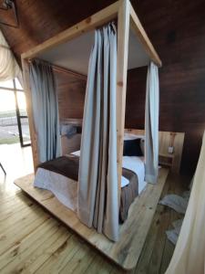 um quarto com uma cama de dossel e cortinas azuis em CABANAS CHEIRO DE MATO em Cambará