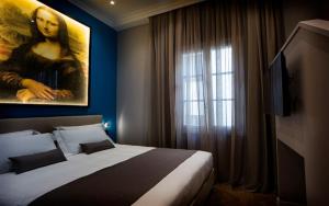 um quarto com uma cama com um quadro de uma mulher em The Frame Hotel em Florença
