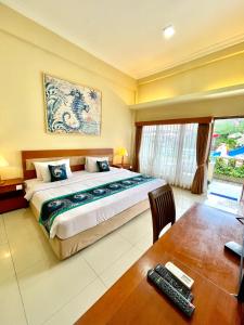 a bedroom with a bed and a desk and a table at Marine Bay Sanur in Sanur