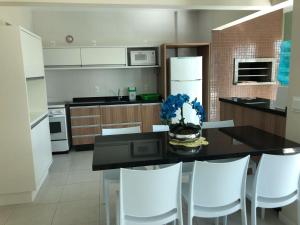 La cuisine est équipée d'une table avec des chaises blanches et d'un réfrigérateur. dans l'établissement Apartamento a 150 metros do mar, à Governador Celso Ramos