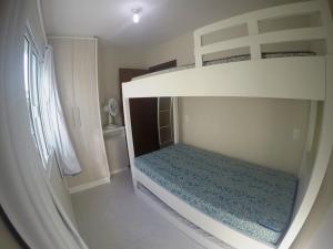 Ce lit superposé blanc se trouve dans une chambre blanche. dans l'établissement Apartamento a 150 metros do mar, à Governador Celso Ramos