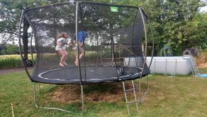 a man and woman playing on a trampoline at Campingspots to put on your own tent with or without electricity, with no bed for 12 euro or 25 euro and 2 furnished glampingtents for minimum 75 euro in a green and peaceful environment between Antwerp and Brussels 