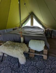 a tent with a bed and two chairs in it at Campingspots to put on your own tent with or without electricity, with no bed for 12 euro or 25 euro and 2 furnished glampingtents for minimum 75 euro in a green and peaceful environment between Antwerp and Brussels 