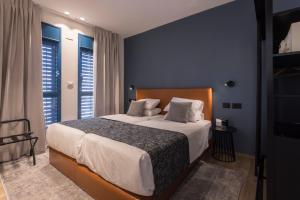 AMALON Boutique Apartments في القدس: غرفة نوم بسرير كبير بجدران زرقاء ونوافذ