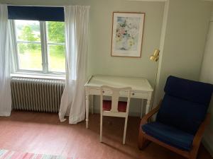 Zimmer mit einem Tisch, einem Stuhl und einem Fenster in der Unterkunft Gåvetorps Gård in Alvesta