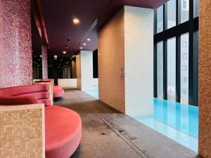 a lobby with pink chairs and a pool in a building at Sweet Home Apartment Melbourne CBD in Melbourne