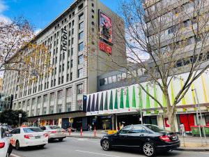 een drukke straat met auto's geparkeerd voor een gebouw bij Sweet Home Apartment Melbourne CBD in Melbourne