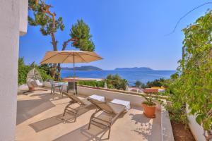 eine Terrasse mit einem Tisch, Stühlen und einem Sonnenschirm in der Unterkunft Gardenia Hotel in Kaş