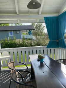a wooden table and chairs on a porch with a blue curtain at Rajskie Domki in Sadowie