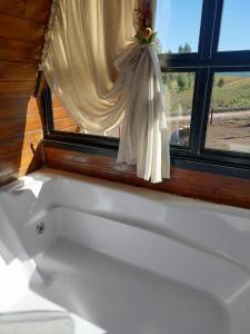 eine weiße Badewanne in einem Zimmer mit Fenster in der Unterkunft CABANAS CHEIRO DE MATO in Cambará