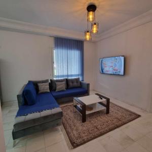 a living room with a blue couch and a table at City View, Ennasr Spacious s2 Apartment in Ariana