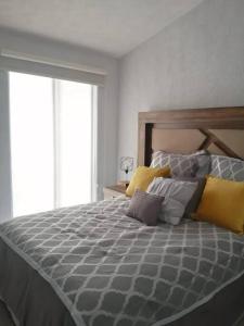 1 dormitorio con 1 cama grande con almohadas amarillas y grises en Casa como nueva, cómoda y tranquila, en Guadalajara