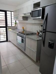 cocina con nevera de acero inoxidable y microondas en Casa como nueva, cómoda y tranquila, en Guadalajara