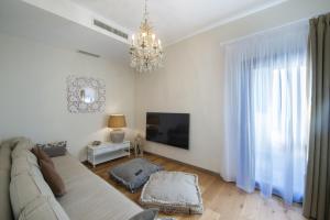 a living room with a couch and a tv and a chandelier at Villa il Giardino - Homelike Villas in Greve in Chianti
