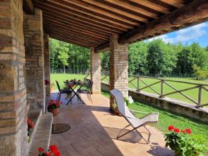 un patio con mesa y sillas bajo un techo de madera en Villa Il Fontanino, en Monticiano